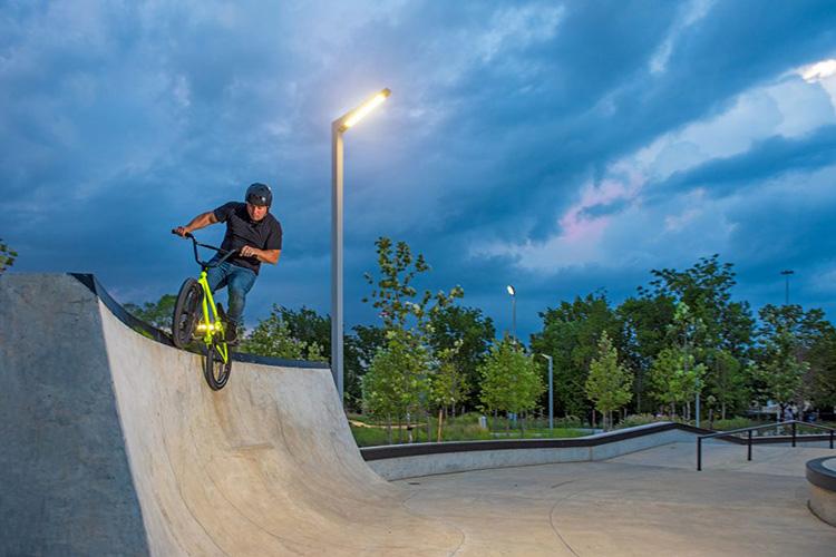 BMX biker grinding the rails in a bike park lit by architectural area lighting